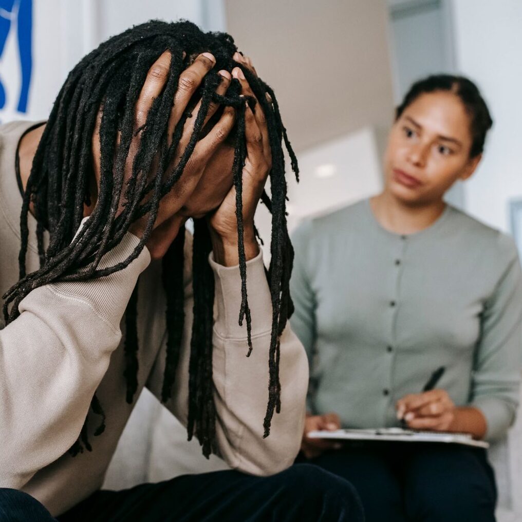 Anonymous frustrated African American male touching head near serious female partner with clipboard while interacting in room