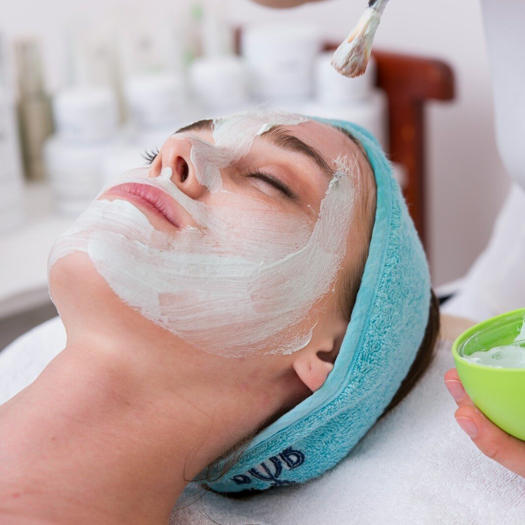 woman lying on blue towel with white cream on face